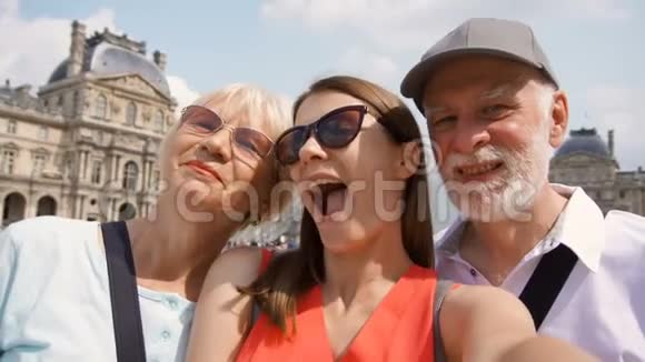 在巴黎度假时一家高年级男女和女儿在智能手机上自拍视频的预览图