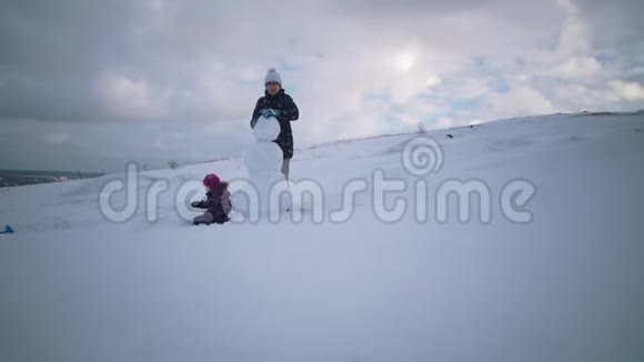 妇女和儿童一起在山上雕刻一个雪人视频的预览图