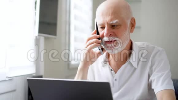 老人坐在家里手提电脑和智能手机在屏幕上用手机讨论项目视频的预览图