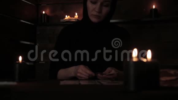 神秘美丽的修女穿着黑色的裙子用黑色烛光在卡片上占卜视频的预览图