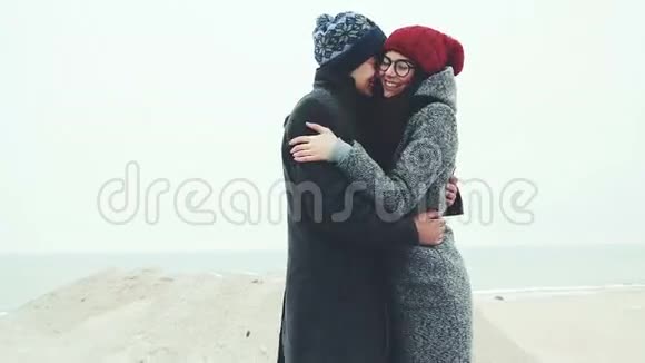 年轻夫妇站在冬天的海滩上搓着手视频的预览图