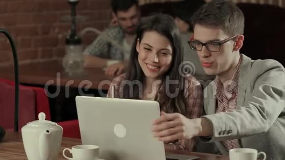 两个人一边笑着一边在笔记本电脑上讲视频视频的预览图
