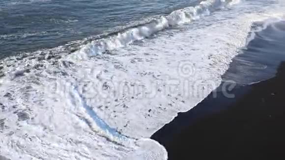 波浪跑到海滩上白色泡沫从黑色海滩的背景上的波浪海洋冲浪视频的预览图