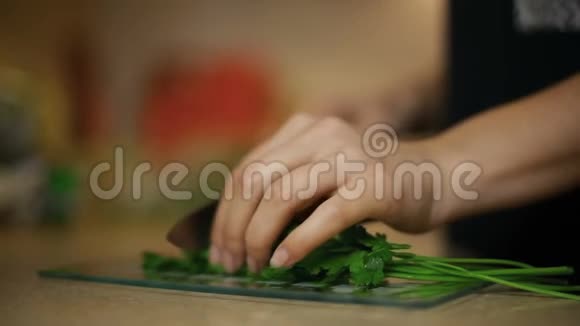 女青年在厨房的玻璃板上切欧芹视频的预览图
