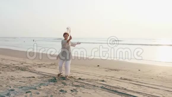日落时分一位资深女士在海滩上练习太极气球视频的预览图
