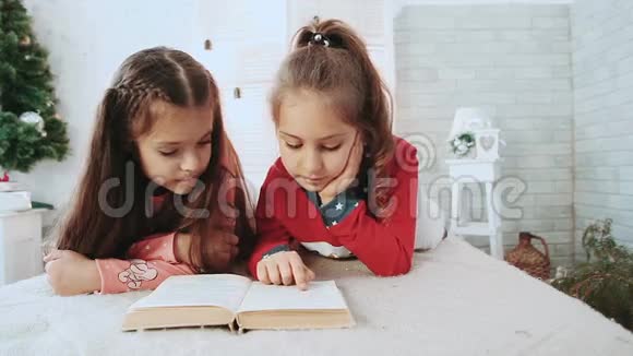 两个孩子坐在一个白色的房间里在背景绿树下看书视频的预览图