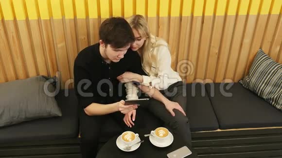 一对快乐的情侣坐在咖啡店在平板电脑上上网视频的预览图