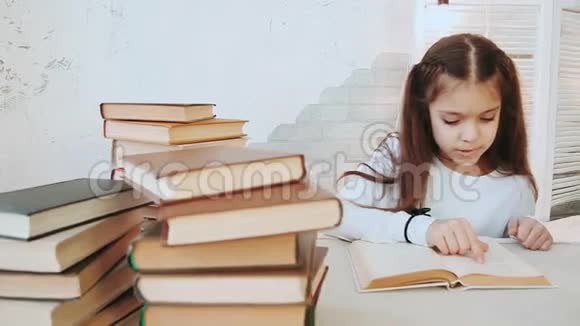 有着美丽的黑发的女孩坐在桌子旁阅读文学作品视频的预览图