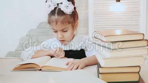 女学生坐在一张桌子旁一边看书一边打哈欠视频的预览图