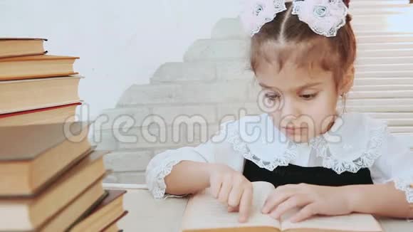 一个坐在桌子旁的孩子用手指穿过前景书堆里的书页视频的预览图