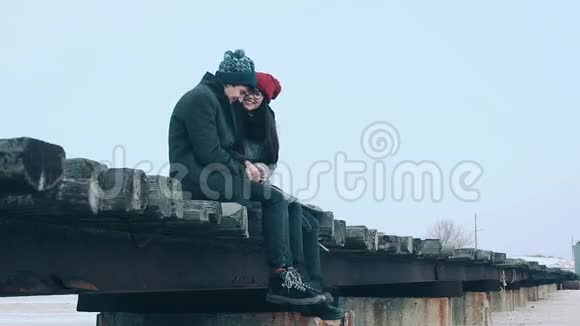 两个情人浪漫的男人坐在桥上他们拥抱和亲吻视频的预览图
