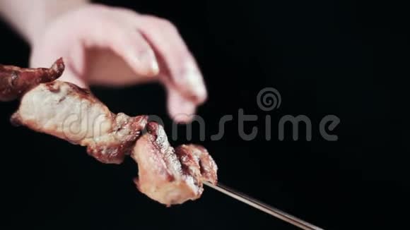 把食物夹起来手从扦子中取出什什串烤肉碎肉什什烤肉串黑色背景视频的预览图