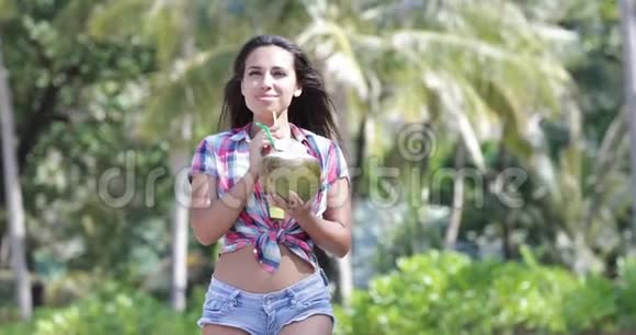 美丽的女孩喝椰子鸡尾酒棕榈树上快乐的微笑青年妇女旅游视频的预览图
