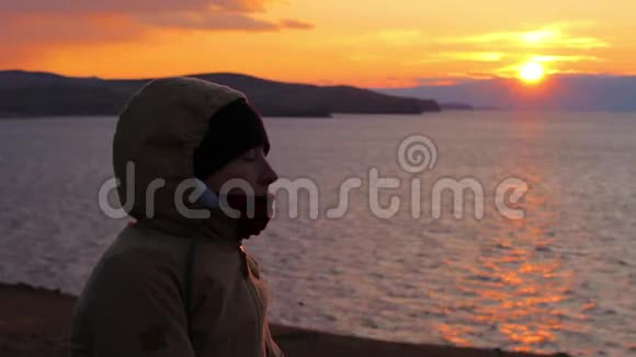 女孩坐在海边沉思美丽的金色夕阳视频的预览图