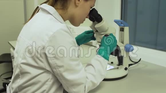 女性生物学家在显微镜下观察视频的预览图