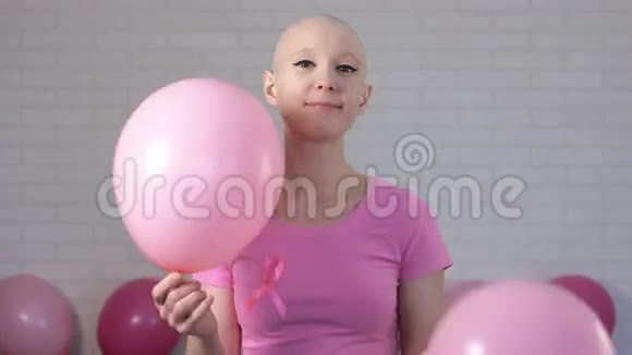 快乐的乳腺癌幸存者女人微笑着看着相机玩着粉红色的气球乳腺癌意识视频的预览图