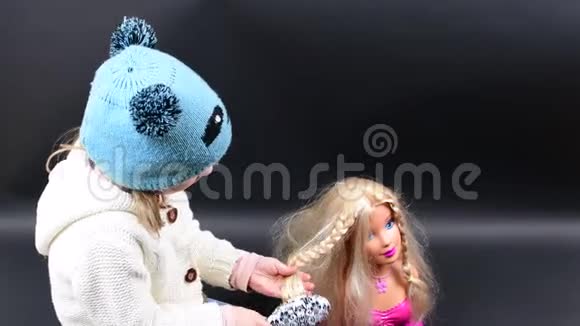 可爱的女孩梳头造型小女孩穿着冬天的衣服可爱的黑背景小女孩视频的预览图