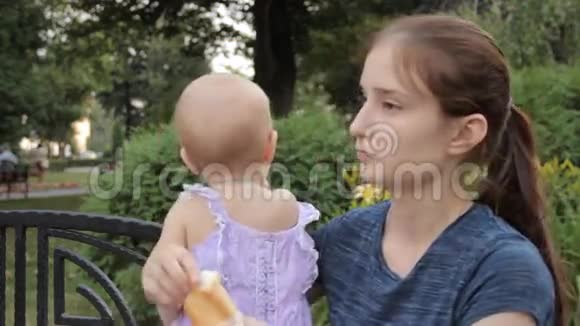一个年轻的保姆在照看一个小女孩的同时挑选一个小包并把它们放进嘴里视频的预览图