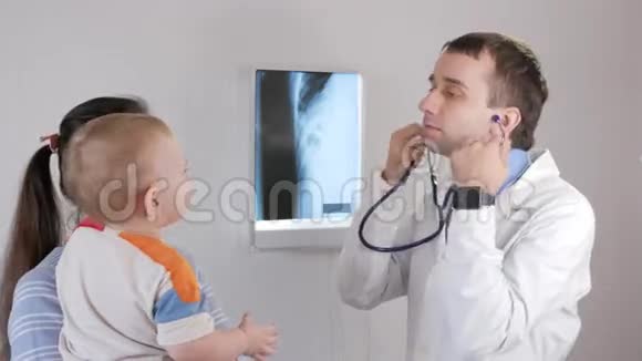 一位年轻的医生检查婴儿肺部他从肚子里和后面听宝宝的微笑视频的预览图