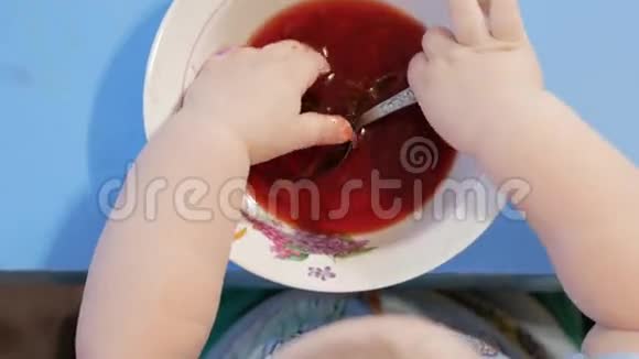 一个2岁有魅力的男孩自己在吃红汤他把手伸进盘子里桌面视图视频的预览图