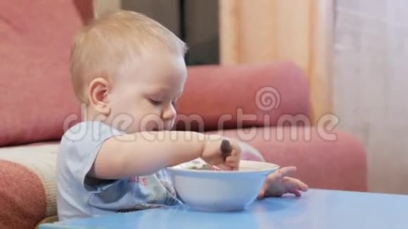 一个2岁有魅力的男孩自己在吃红汤勺子和手流动的液体健康饮食的概念视频的预览图