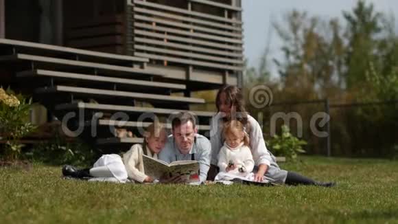 快乐的一家人坐在草地上夏天在草坪上休息全高清视频的预览图