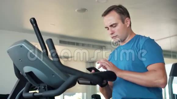 帅哥适合在健身房做运动的年轻人用智能手机和朋友聊天视频的预览图