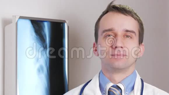一位年轻的医生看着相机微笑背景下悬挂患者x线带领带的衬衫视频的预览图