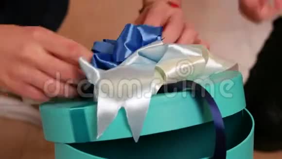 礼物包装女孩在盒子上编织蝴蝶结带礼物圣诞节的节日惊喜或生日礼物准备视频的预览图