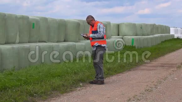农民在干草堆附近的农村公路上使用智能手机视频的预览图