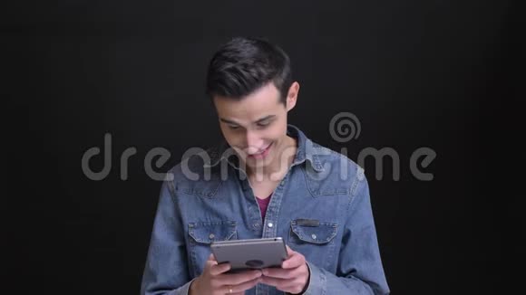特写白种人年轻帅哥在镜头前的平板电脑上浏览的照片背景是孤立的视频的预览图