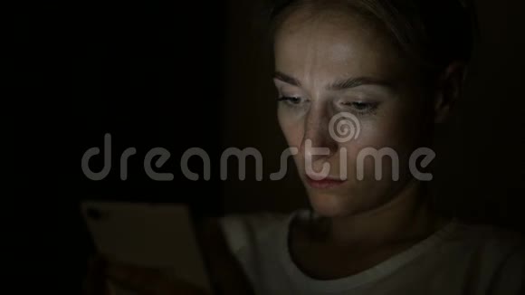 疲倦悲伤的女人晚上用手机视频的预览图