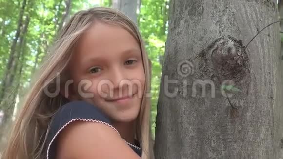 在森林里的孩子在大自然中玩耍的孩子在户外冒险的女孩在树后面视频的预览图
