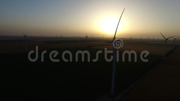 太阳落山时麦田里的风力涡轮机剪影航空测量视频的预览图