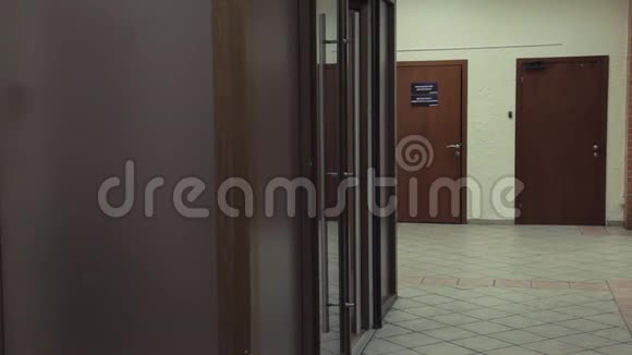 年轻漂亮的女人打开玻璃门走进办公室走廊视频的预览图