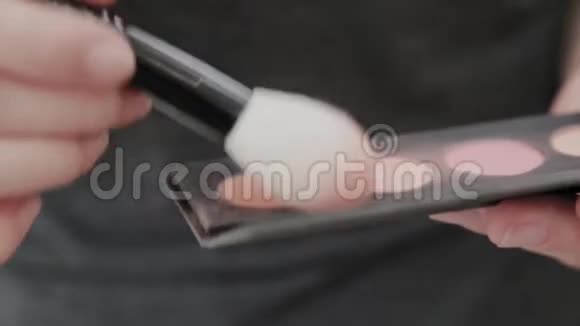 专业化妆师女人把粉涂在刷子上视频的预览图