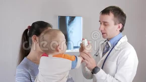 一位年轻的男性儿科医生开药并给药这个男孩在他母亲怀里一位年轻女子专心听讲视频的预览图