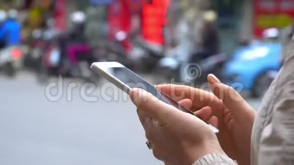 在城市中使用智能手机的亲密女性背景上轻快的路越南视频的预览图