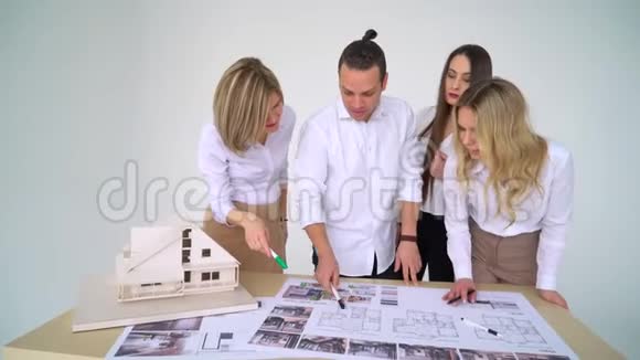 四位建筑师在办公桌上讨论设计图的特写镜头视频的预览图
