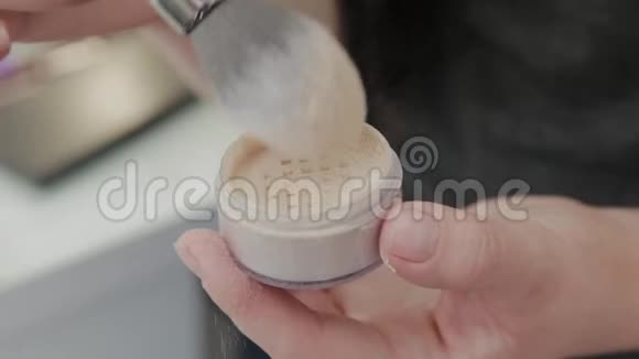 专业化妆师女人把粉涂在刷子上视频的预览图