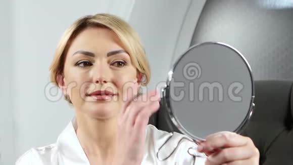 女人握着镜子在嘴唇上做脱毛视频的预览图
