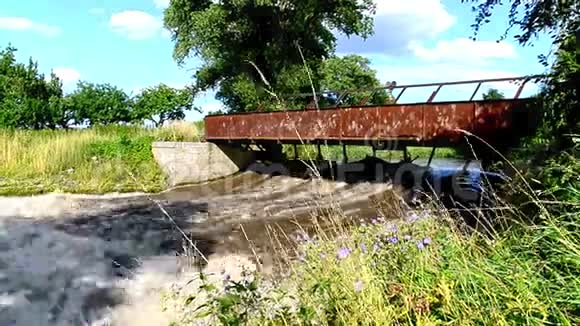 一座古老的锈迹斑斑的桥在一条带着暴风雨水的小溪上视频的预览图