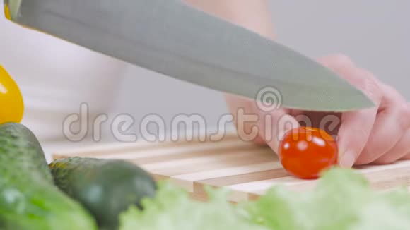 一个女人在分割的木板上用刀切一个樱桃番茄视频的预览图