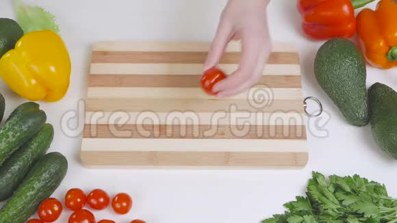 一个女人在分割的木板上用刀切一个樱桃番茄视频的预览图