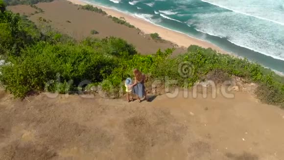一名年轻女子和她的儿子在巴厘岛的一个偏僻的海滩上访问了纽约站在岩石上视频的预览图