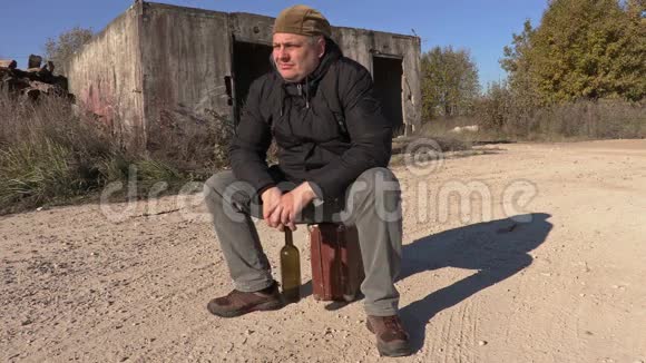 沮丧的男人拿着酒瓶坐在手提箱上视频的预览图