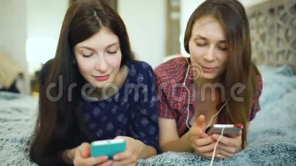 两位元女朋友用耳机听音乐耳机连接到手机上躺在床上视频的预览图