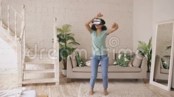 快乐的微笑年轻混合种族女孩获得体验使用虚拟现实耳机眼镜和在家跳舞视频的预览图