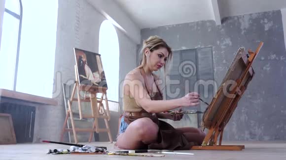 女艺术家坐在地板上画画画室里的画视频的预览图