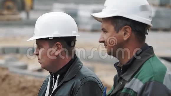 两个戴着白色安全帽的男人在建筑工地集中注意力视频的预览图